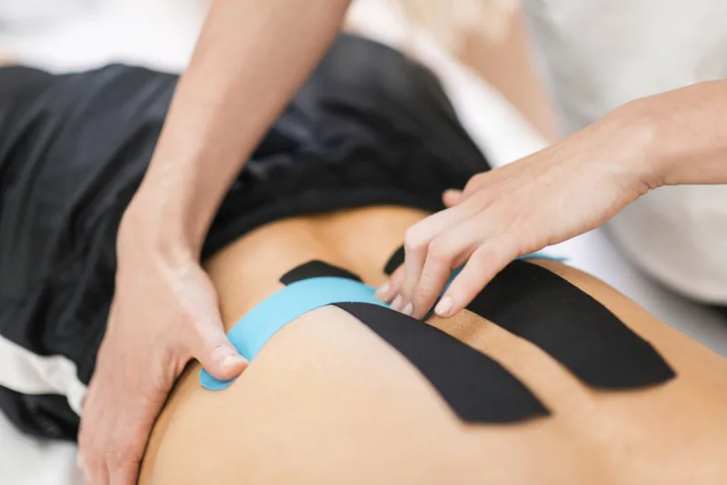 Kinesiology tape being applied to the lower back